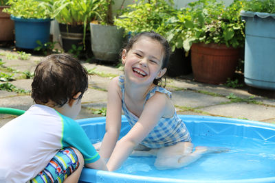 Siblings playing in a shallow pool in the backyard