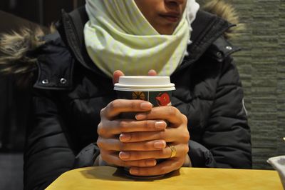 Midsection of woman holding coffee cup