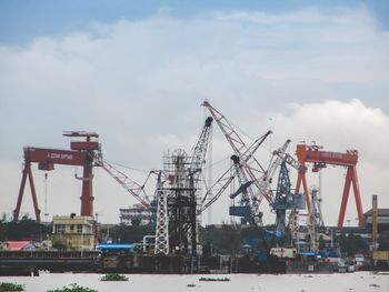 Cranes at commercial dock against sky