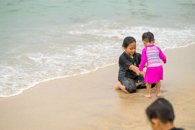 Siblings playing with sand at beach