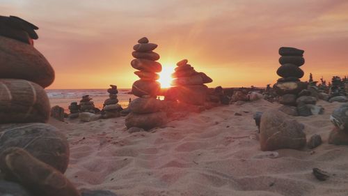 Rocks on beach against sky during sunset