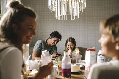 Happy father and daughter using smart phone at dining table