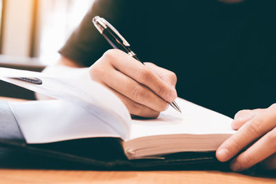 Close-up of businesswoman writing in book