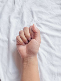 Close-up of human hand on bed