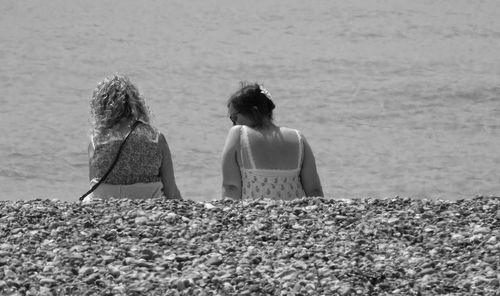 Rear view of women sitting on beach