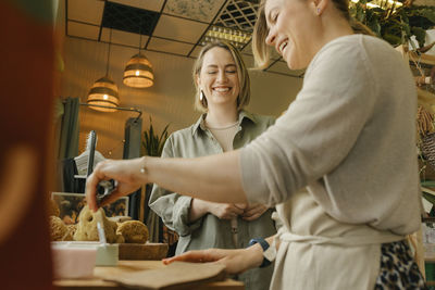 Smiling owner cutting bar of soap for customer in eco-shop