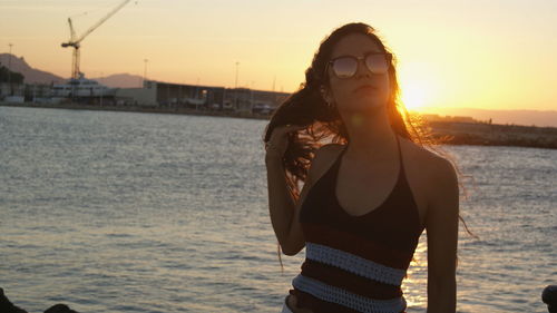 Portrait of woman standing at beach against sky during sunset