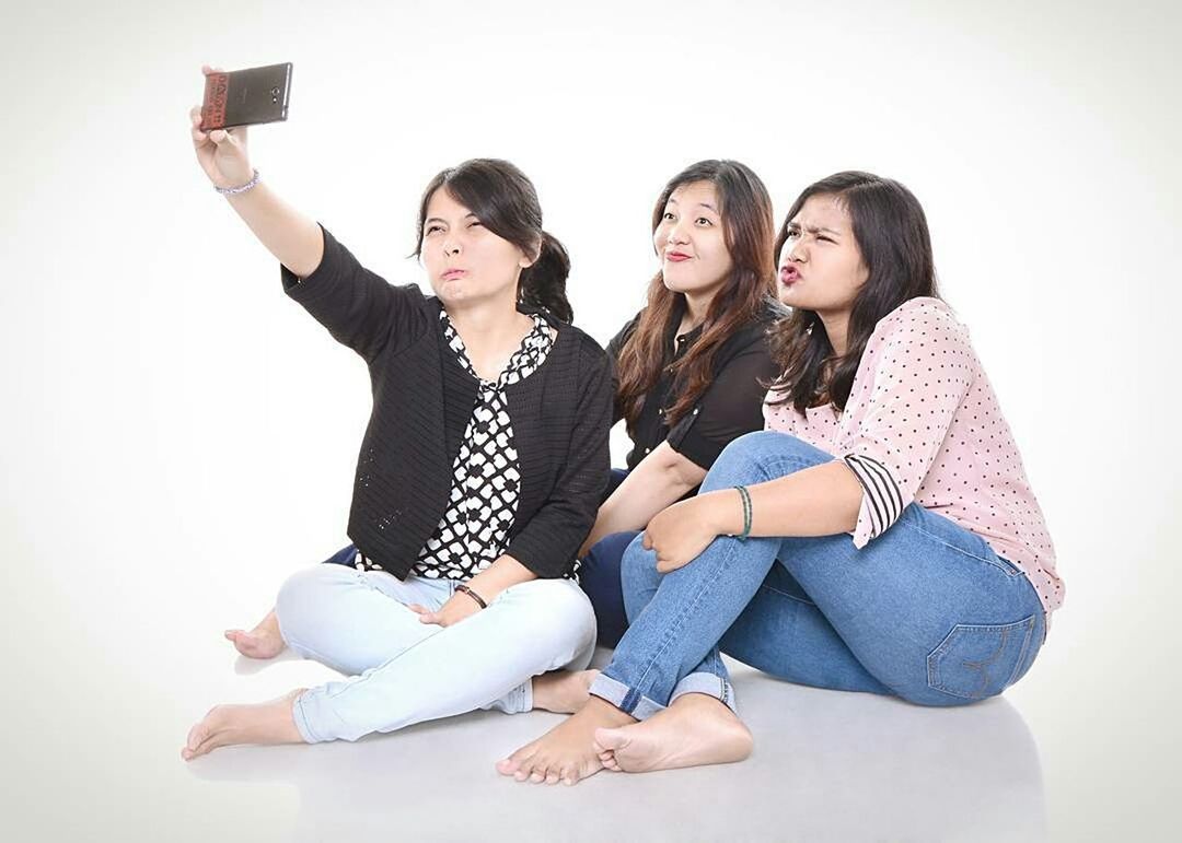 wireless technology, photography themes, selfie, smart phone, photo messaging, mobile phone, portable information device, communication, photographing, friendship, telephone, people, teenager, full length, digital native, togetherness, white background, happiness, technology, smiling, young adult, cheerful, adult, adults only