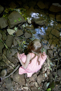High angle view of girl by stream on rocks
