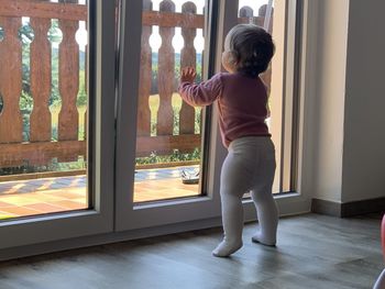 Rear view of girl standing by window