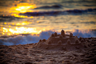 Sandcastle against sea during sunset