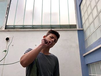 Portrait of man smoking cigarette against wall