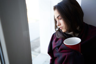 Side view of young woman drinking coffee at home