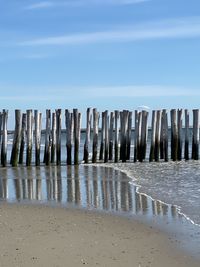 Wooden posts on beach against sky