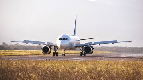 Airplane on airport runway against sky