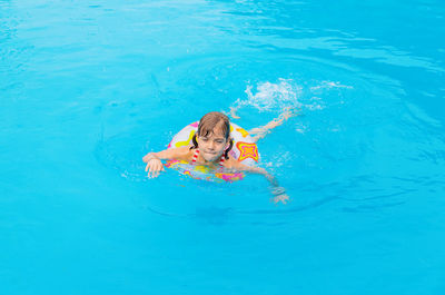 Girl swimming with inflatable ring in blue pool