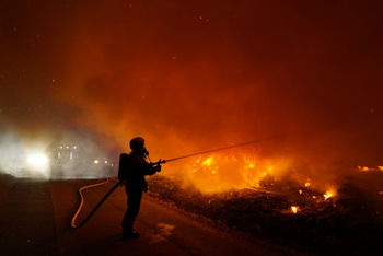 Silhouette firefighter against fire at night