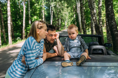 Mom, dad and little son in a convertible car. summer family road trip to nature