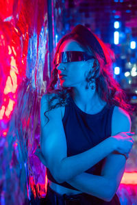 Portrait of young woman wearing sunglasses while standing against christmas tree