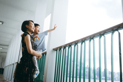 Low angle view of women standing by railing against sky