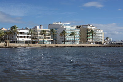 Buildings by sea against blue sky