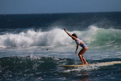 Young woman surfing on sea