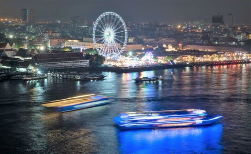 Illuminated ferris wheel in city at night