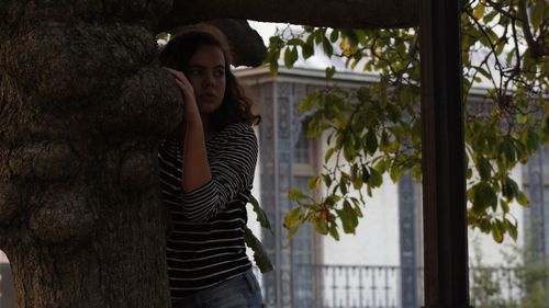 Young woman standing by tree