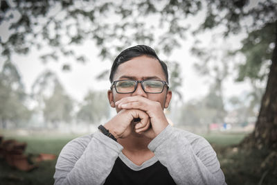 Portrait of man in eyeglasses against trees