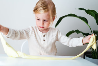 Portrait of cute girl playing with slime at home 