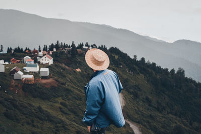 Rear view of woman standing on mountain against sky