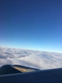 Airplane flying over clouds against blue sky