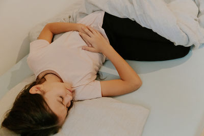 Low section of woman lying on bed at home