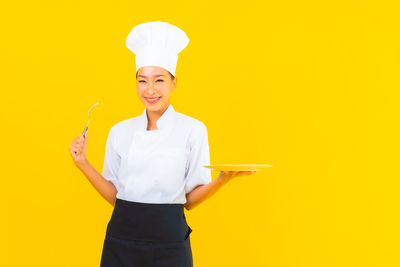 Portrait of a smiling young woman against yellow background