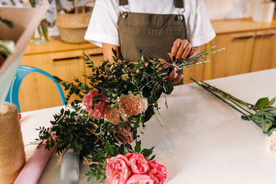 Midsection of woman holding flower bouquet on table