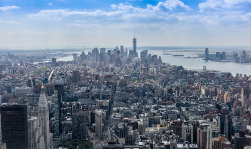 Cityscape by east river against cloudy sky