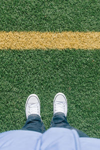 Low section of man standing on grassy field