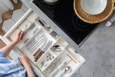 Midsection of woman opening drawer in kitchen
