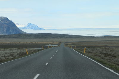 Road leading towards mountains against sky
