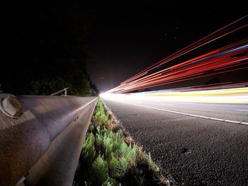 Light trails on road against sky at night