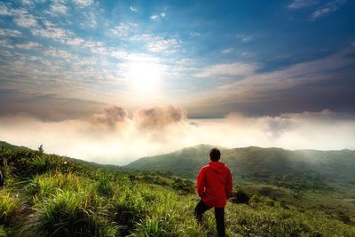 Rear view of man standing on mountain against sky