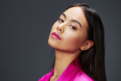 Close-up of young woman against black background