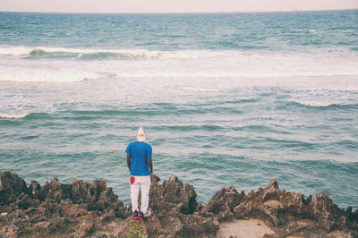 Rear view of man standing on beach against sky