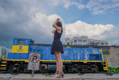 Rear view of man standing on railroad track against sky