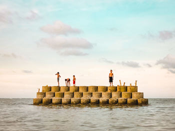 People standing by sea against sky