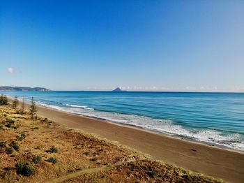 Scenic view of beach against clear blue sky