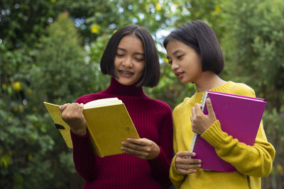 Portrait of a smiling young woman reading book