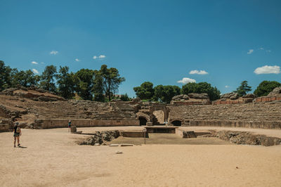 People walking around the arena of roman amphitheater in a sunny day at merida, spain
