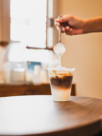 Cropped hand of woman holding coffee on table