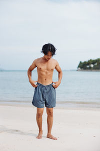 Rear view of shirtless man standing at beach